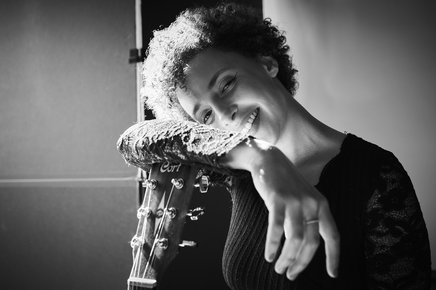 Black and white portrait of Noeme smiling with her guitar
